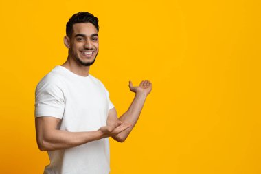 Gülümseyen Orta Doğulu adam reklam için kopya alanı gösteriyor.