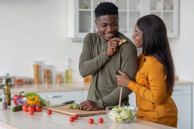 Afro-Amerikan çifti sıcak mutfakta birlikte yemek hazırlıyor.