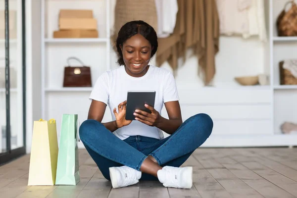 바닥에 앉아 있는 디지털 타블렛을 사용하여 쇼핑하는 아프리카 여자 — 스톡 사진