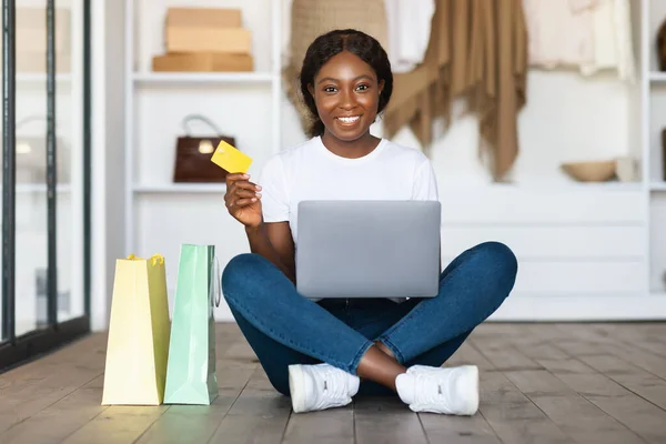 Mujer negra de compras en línea usando el ordenador portátil y la tarjeta de crédito en interiores — Foto de Stock