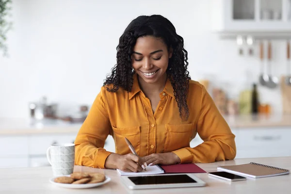 Positieve zwarte dame freelancer werken vanuit huis, notities maken — Stockfoto