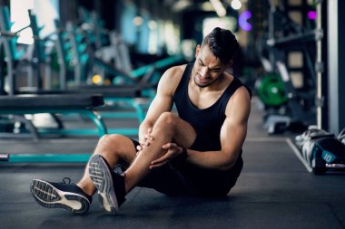 Spor sakatlığı. Spor salonunda eğitim gören Arap erkek sporcu diz travması geçiriyor