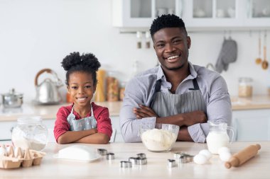 Kendine güvenen baba ve çocuk evde pasta yaparken poz veriyorlar.