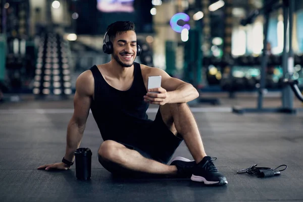 Aplicação de treino. Feliz árabe masculino atleta usando Smartphone depois de treinar no ginásio — Fotografia de Stock