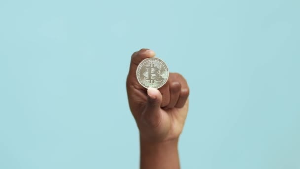 Černá ženská ruka drží stříbrný bitcoin kryptoměna na modrém pozadí — Stock video