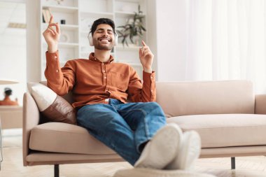 Şarkı söyleyen, dans eden, kablosuz kulaklık takan mutlu bir Arap.