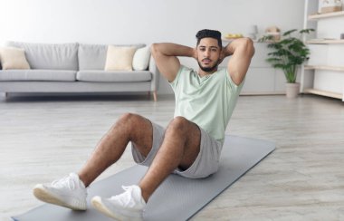 Sportif bin yıllık Arap adam iç eğitim sırasında karın kasları egzersizi yapıyor.