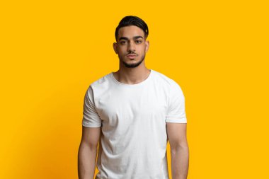 Sarı stüdyo arka planında poz veren yakışıklı bir orta doğulu.