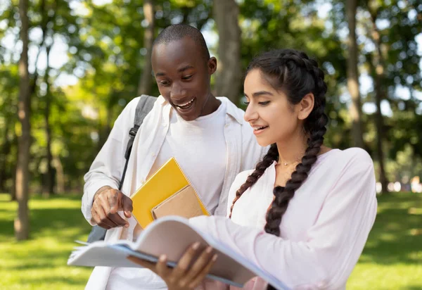 Learning concept. Multiracial student guy and lady preparing for classes, studying with books in university campus