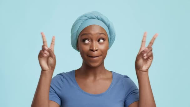 Веселый афроамериканский женский жест V знак над синим фоном — стоковое видео