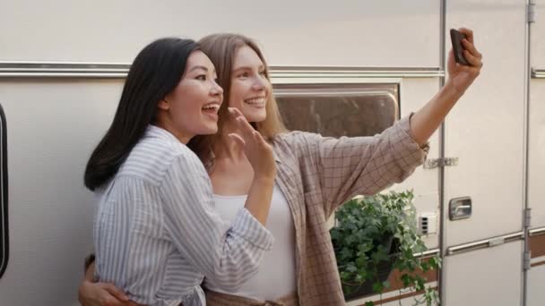 Dos amigas alegres sonriendo y tomando selfie en el smartphone en el camping — Vídeos de Stock