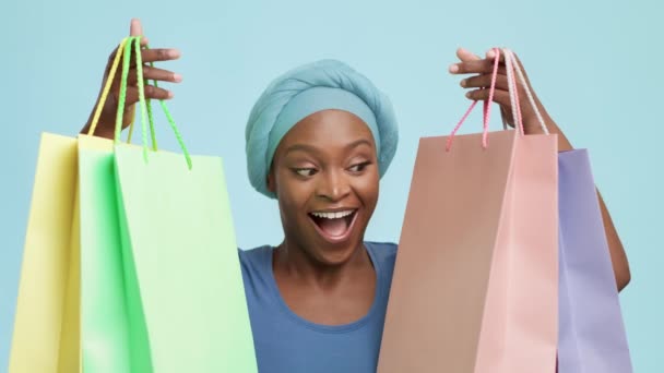 Joyful Black Lady Segurando coloridos sacos de compras em fundo azul — Vídeo de Stock