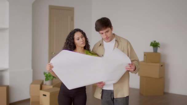 Manželé drží papír s plánem obnovy stojící v novém domově — Stock video