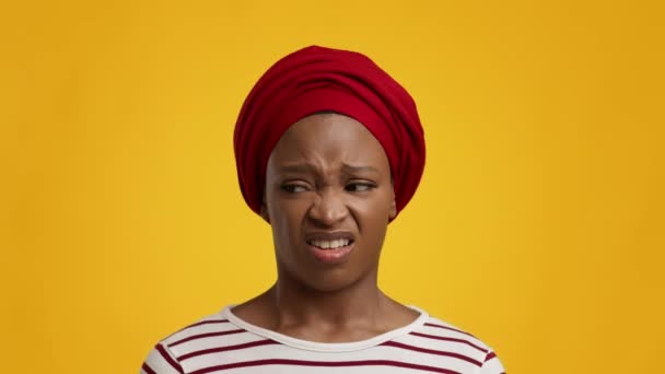 Ekelhafte Afrikanerin, die unangenehmen Gestank riecht, trägt Kopftuch, gelber Hintergrund — Stockvideo