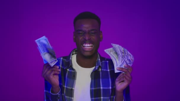 Africano americano cara segurando dinheiro cheirando Shaking dinheiro, fundo roxo — Vídeo de Stock