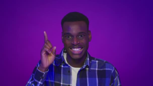 Negro chico señalando dedo arriba tener idea sobre púrpura fondo — Vídeo de stock
