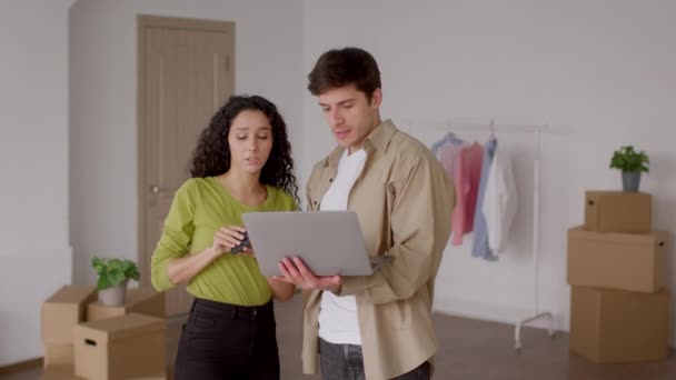 Coppia guardando soffitto, chiamando utilizzando il computer portatile in una nuova casa — Video Stock