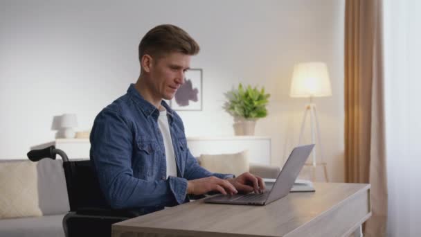 Online work opportunities for people with disability. Zoom in portrait of man wheelchair user typing on laptop at home — Stock Video