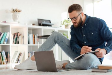 Millennial Guy evdeki laptopa bakarak not alıyor.
