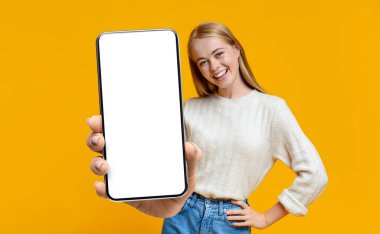 Boş beyaz ekran ile akıllı telefon sergileyen heyecanlı kadın, ilanınız, web siteniz ya da uygulama tasarımınız için yer gösteriyor