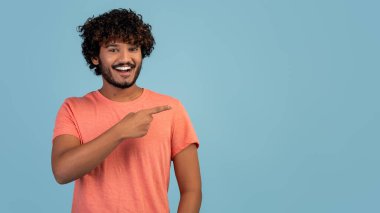 Pembe elbiseli neşeli Hintli adam fotokopi alanını işaret ediyor.