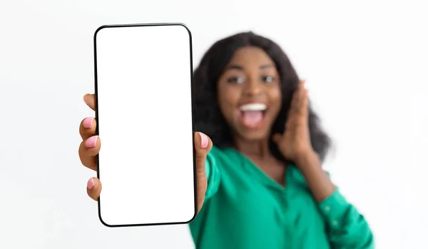 Vaya, una aplicación increíble. Emocionada dama afroamericana sosteniendo teléfono inteligente con pantalla en blanco en la mano, mostrando dispositivo, maqueta — Foto de Stock