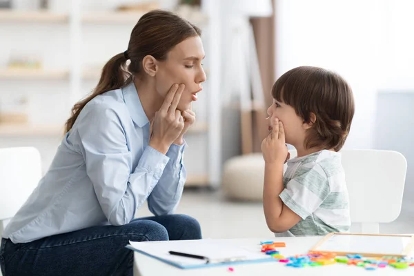 Lindo entrenamiento de niño pequeño con especialista en habla profesional, repetición de ejercicio oral, calentamiento de los músculos de la boca — Foto de Stock