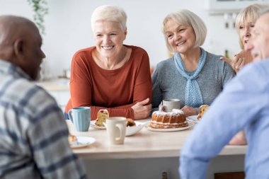 Mutlu son sınıf arkadaşları birlikte çay içip pasta yiyor.