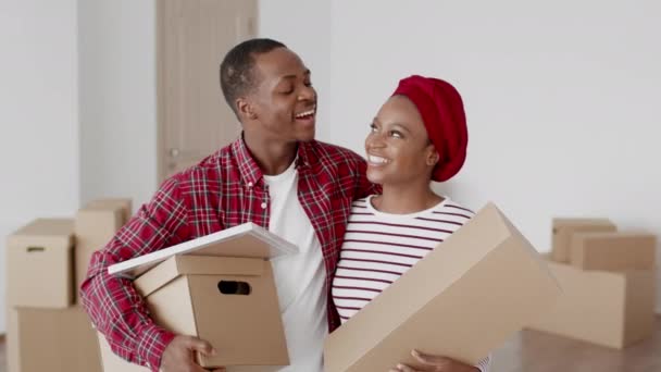 Весёлый чёрный муж и жена, держащие коробки дома — стоковое видео