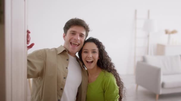 Šťastný pár mává rukou stojící v otevřených dveřích doma — Stock video