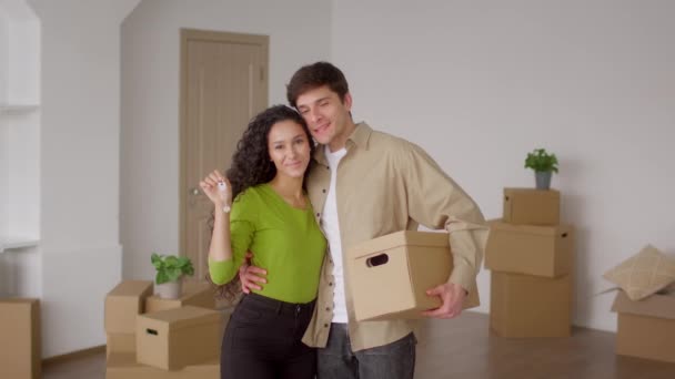 Pasangan Memegang Kunci Rumah Baru Memeluk Kotak Bergerak di Dalam Ruangan — Stok Video