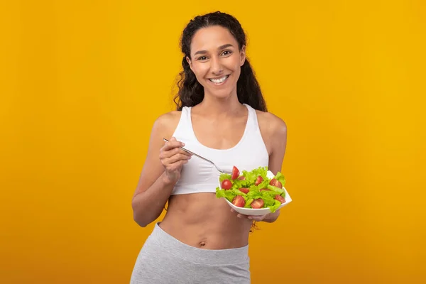 Retrato de sorridente ajuste senhora segurando placa com salada — Fotografia de Stock