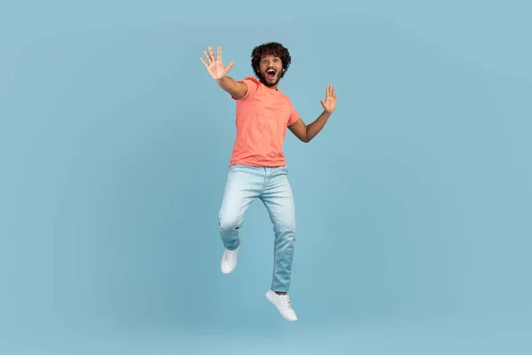 Carefree young indian man jumping over blue — Stock Photo, Image