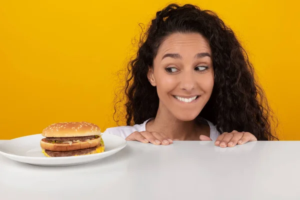 Wanita lapar Melihat Burger Peeping Out Table — Stok Foto