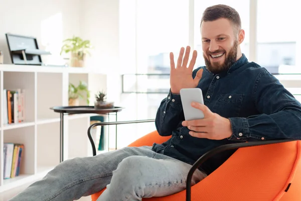 Hombre feliz haciendo videollamada saludando Hola al teléfono interior — Foto de Stock