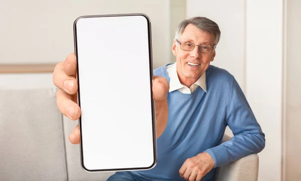 Podekscytowany senior pokazujący duży smartfon z białym, pustym ekranem, polecający stronę internetową lub aplikację, makietę — Zdjęcie stockowe