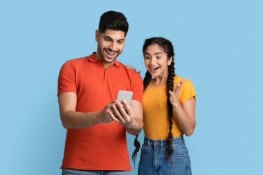 Harika bir uygulama. Şaşırmış Orta Doğulu Çift Heyecanla Akıllı Telefon Ekranına Bakıyor