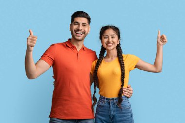 Kameraya başparmak gösteren genç, pozitif orta doğulu bir çift portresi.