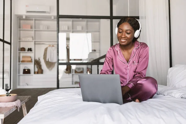 Fröhliche schwarze Frau mit Kopfhörern im Schlafzimmer — Stockfoto