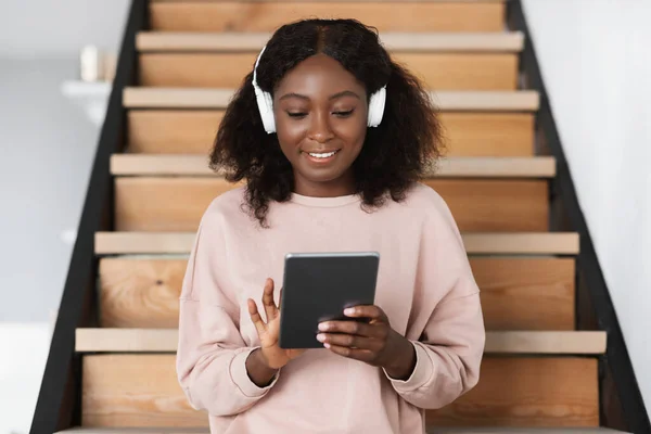 ヘッドフォンを装着したデジタルタブレットを使用して幸せなアフリカ系アメリカ人女性屋内 — ストック写真