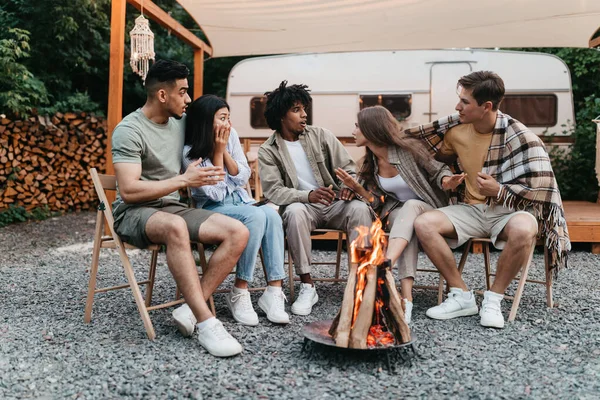 Divers jeunes amis assis près du feu de camp, racontant des histoires effrayantes à côté de VR pendant le voyage de camping en vacances d'été — Photo