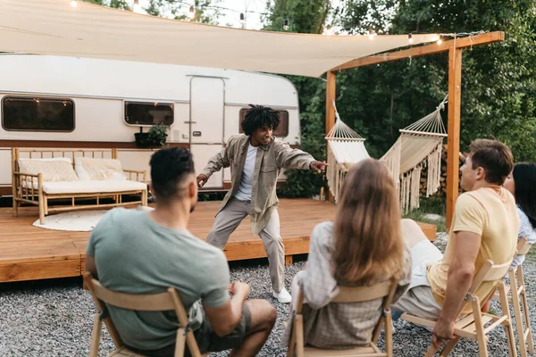 Cool black guy montrant pantomime à ses amis internationaux, jouer jeu de charades près de VR sur le voyage de camping — Photo