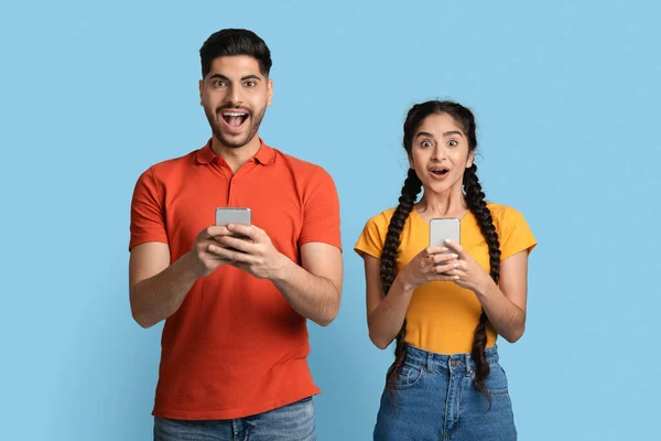 Offre mobile. Portrait de heureux couple arabe choqué avec smartphones dans les mains — Photo