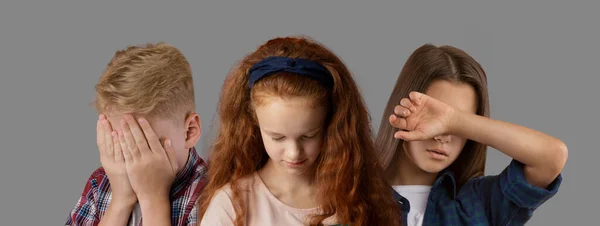 Concepto de niños y emociones. Retrato de niños molestos posando sobre fondo gris — Foto de Stock