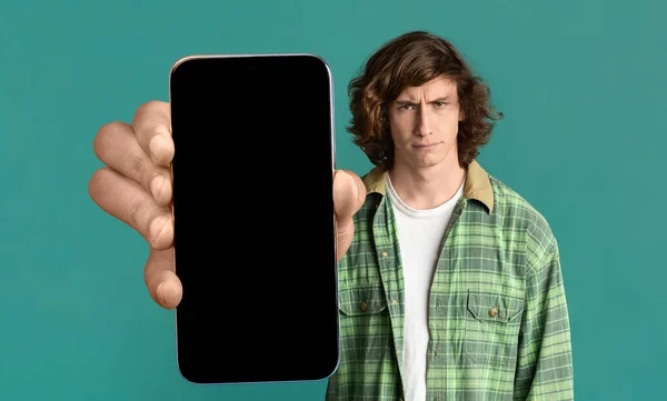 Wütender Millennial Guy hält großes leeres Smartphone mit leerem Bildschirm in der Hand — Stockfoto