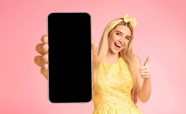 Jovem excitada segurando grande smartphone em branco e mostrando o polegar para cima — Fotografia de Stock