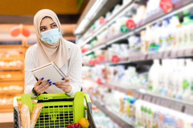 Yüzü maskeli Orta Doğulu Kadın Süpermarkette alışveriş yapıyor.