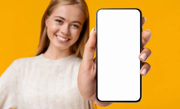 Linda menina adolescente sorridente demonstrando Smartphone com tela branca em branco — Fotografia de Stock