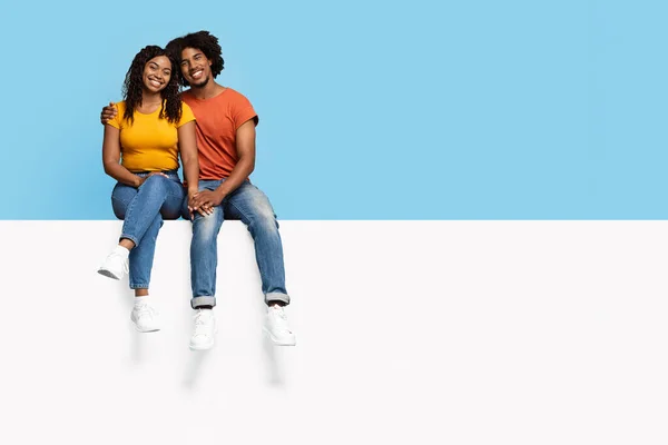 Snygga svarta människor sitter på tom reklamtavla, kramas — Stockfoto