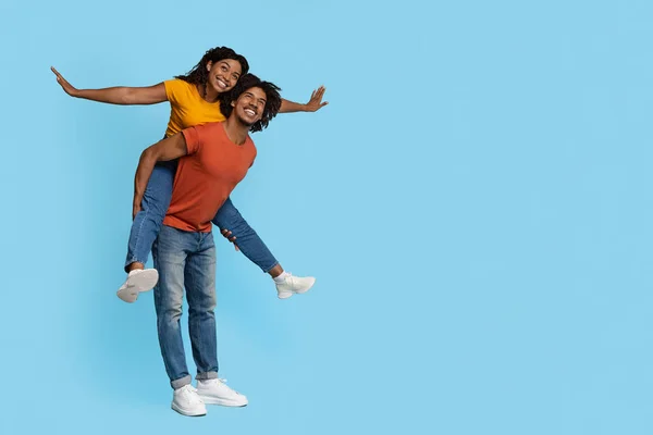 Vrolijke zwarte man meeliften zijn gelukkig vriendin — Stockfoto